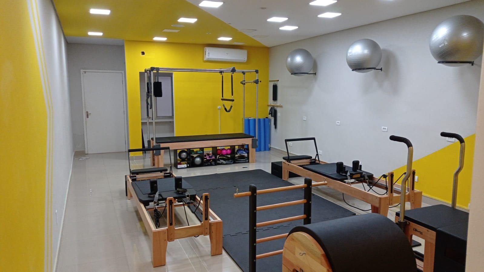 Estúdio de pilates no Tatuapé com cadillac, reformers de madeira e parede amarela