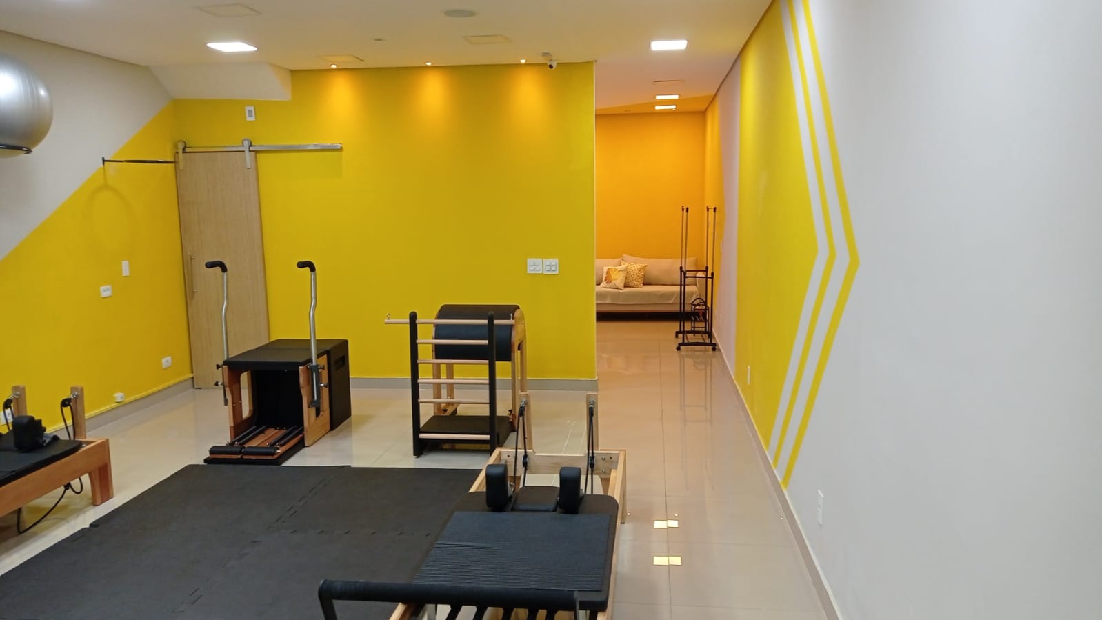 Estúdio de pilates no Tatuapé com cadeira, barrel e vista da espera ao fundo
